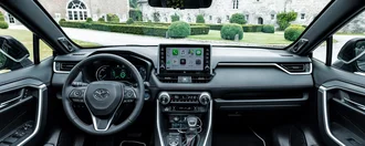 Blick auf das Interieur eines Toyota Rav4, von den sitzen aus fotografiert. Zu sehen sind ein Lenkrad und das Amaturenbrett mit Schaltfläche.