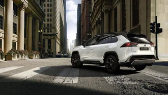 Weißer Toyota Rav4 biegt in Häuserflucht einer modernen Stadt ein