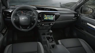 Cockpit des Toyota Hilux - im Hintergrund ein wilder Fluss, an dem ein Angler angelt