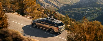 Grauer Toyota auf einer Landstraße in einer bergigen Landschaft von oben fotografiert