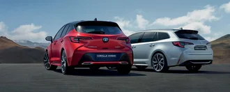 Zwei Toyota Corolla von der Asphaltnabe aus fotografiert vor bergigem Hintergrund