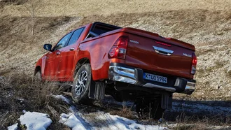 Toyota Hilux, der über eine Kuppe im offenen Gelände fährt