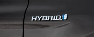 Zu sehen ist eine Nahaufnahme des Wortes HYBRID auf der Seite eines grauen Toyota